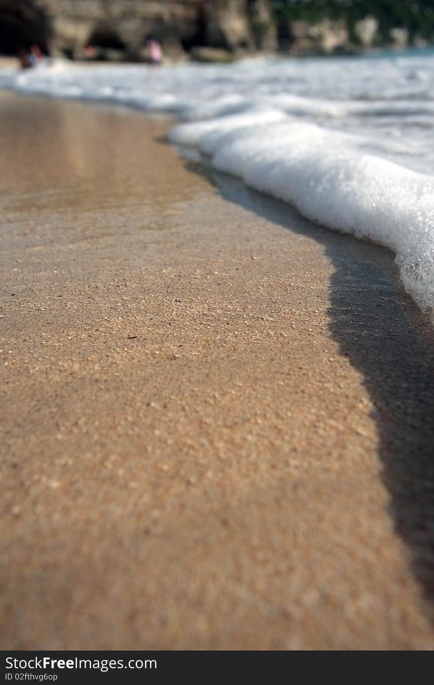 The ocean wave leaves on a sandy beach