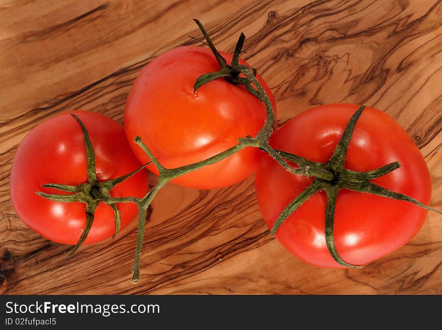 Three fresh red tomato on brown background