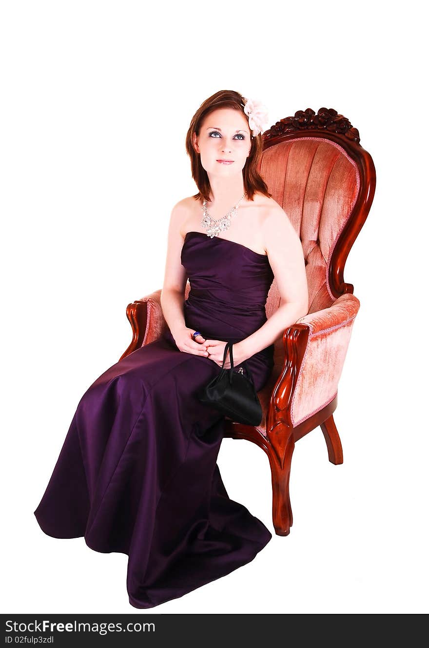 An young pretty woman in a burgundy long evening dress sitting in a 
antic pink armchair for white background. An young pretty woman in a burgundy long evening dress sitting in a 
antic pink armchair for white background.