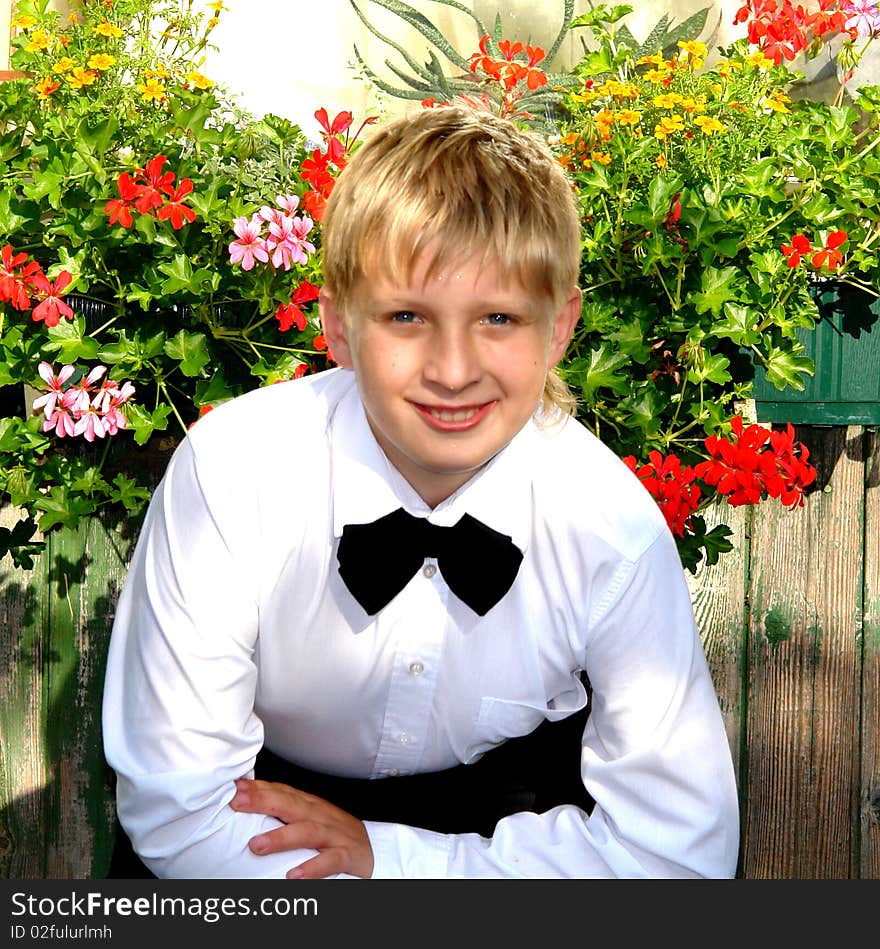 Happy blonde teenager sitting next to flowers. Happy blonde teenager sitting next to flowers