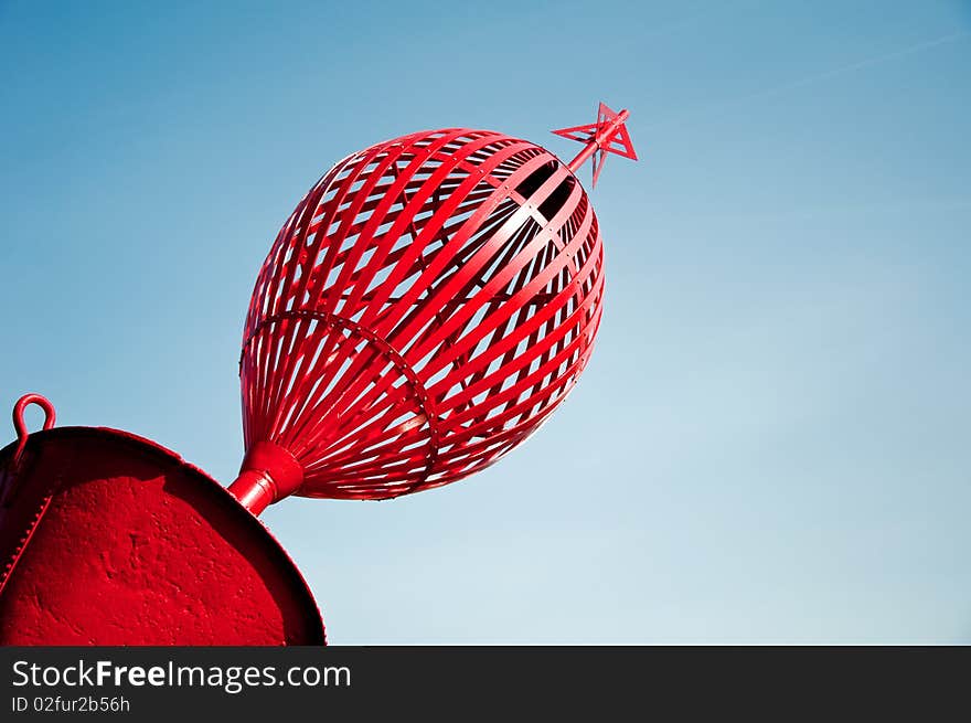 Red navigational mark against a blue sky.