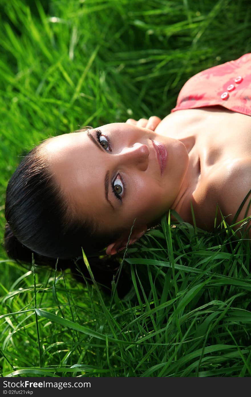 Girl is laying down on a meadow and relax in the green grass. Nice portrait. Girl is laying down on a meadow and relax in the green grass. Nice portrait