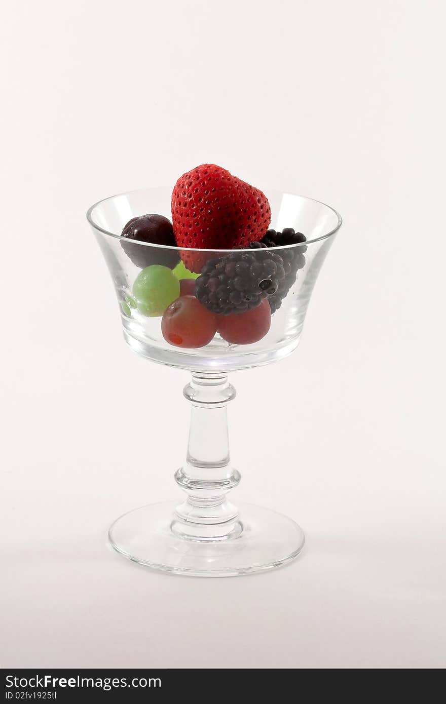 Fresh fruit in a clear crystal glass isolated on white background.