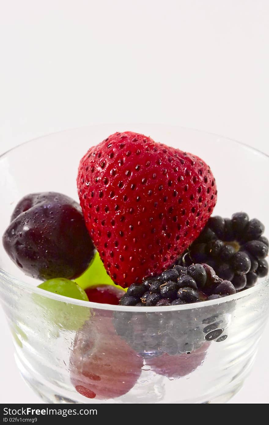 Fresh fruit in a clear crystal glass isolated on white background.