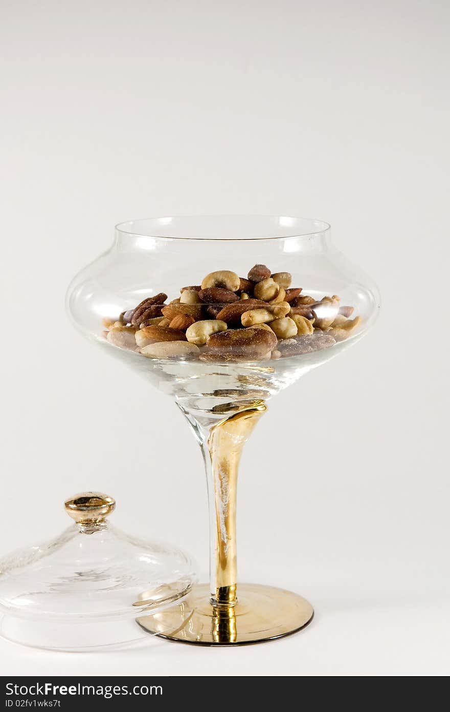 Mixed nuts in a clear crystal bowl on a white background. Mixed nuts in a clear crystal bowl on a white background.