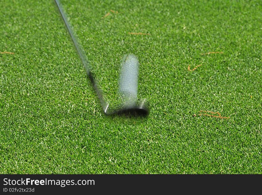 A golf club striking the ball, showing movement. A golf club striking the ball, showing movement