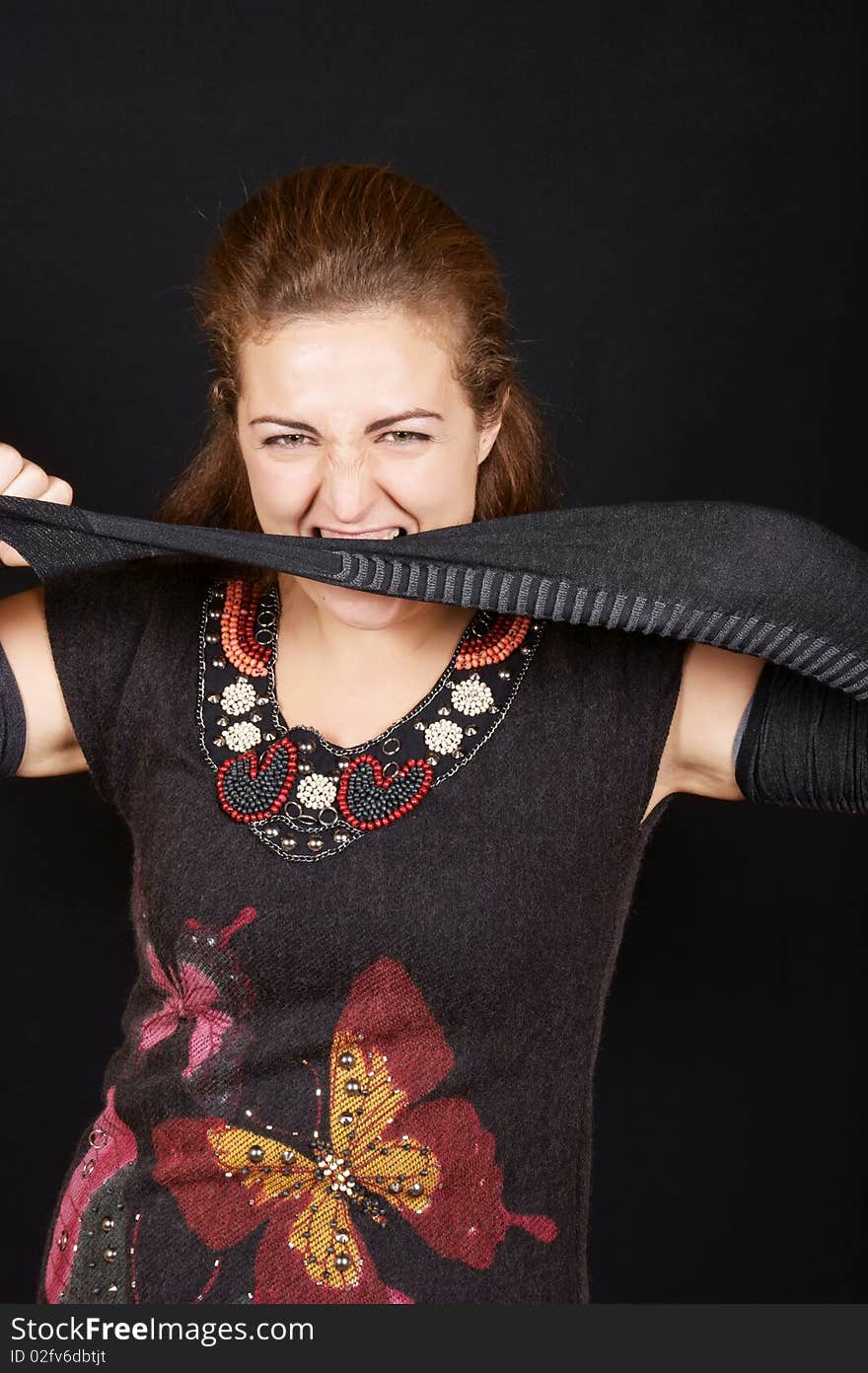 Portrait of a beautiful young woman wearing black dress and gantlets. She's stretching one gantlet and biting it. Studio shot over black background. Portrait of a beautiful young woman wearing black dress and gantlets. She's stretching one gantlet and biting it. Studio shot over black background.