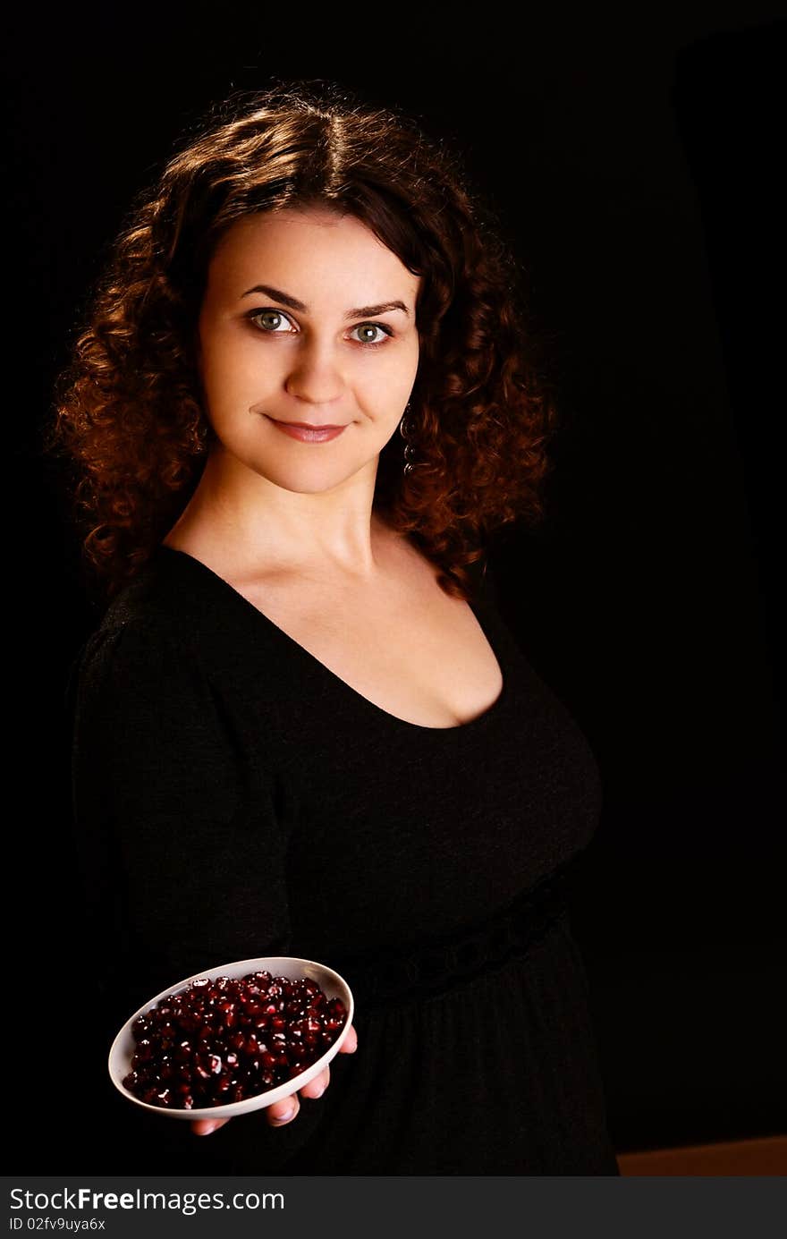 Portrait of a young woman with seeds of pomegranate. Studio shot.