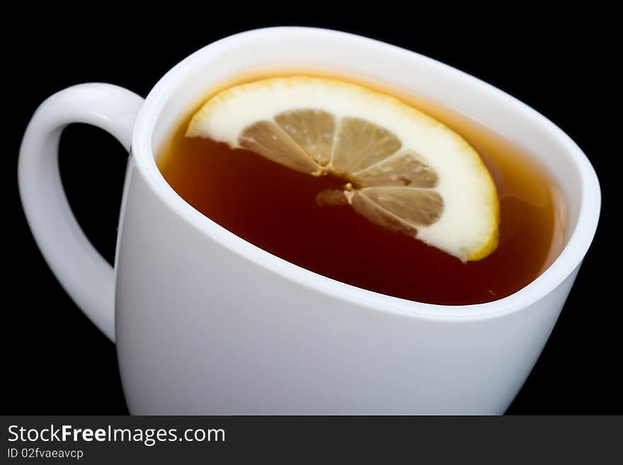 Close-up cup of tea with lemon on black