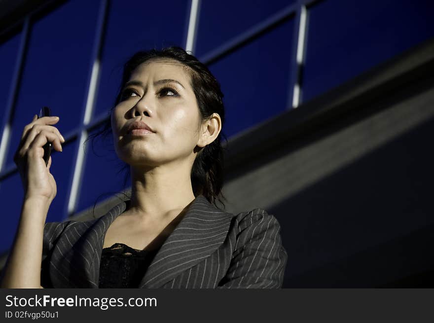 Business woman on the phone with modern office building in background.