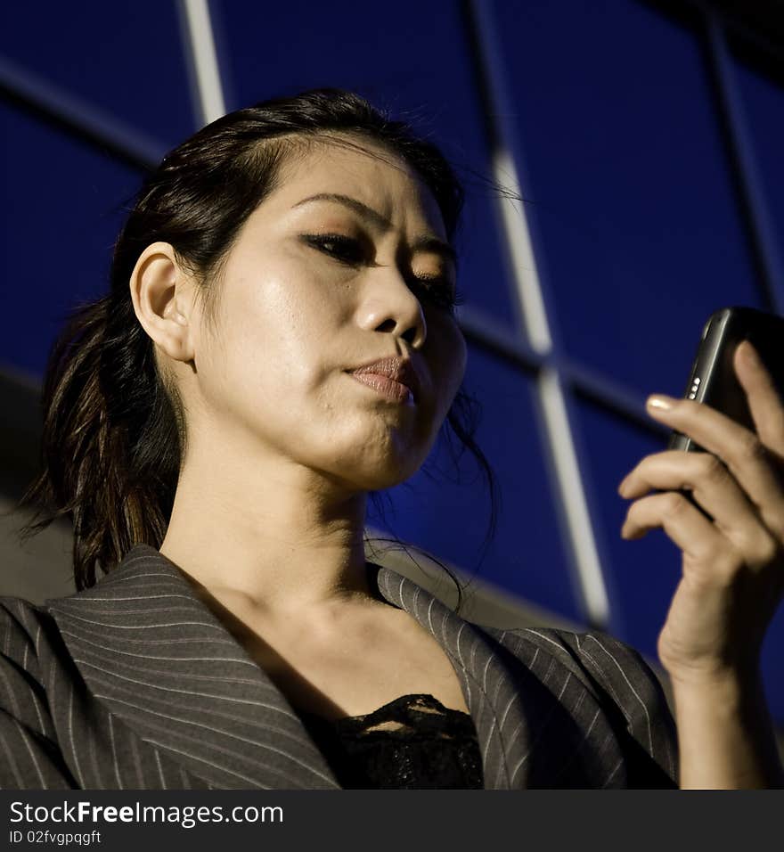 Business woman on the phone with modern office building in background.