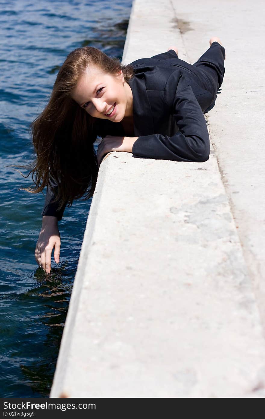 Woman in black suit lying on the border near the water. Woman in black suit lying on the border near the water