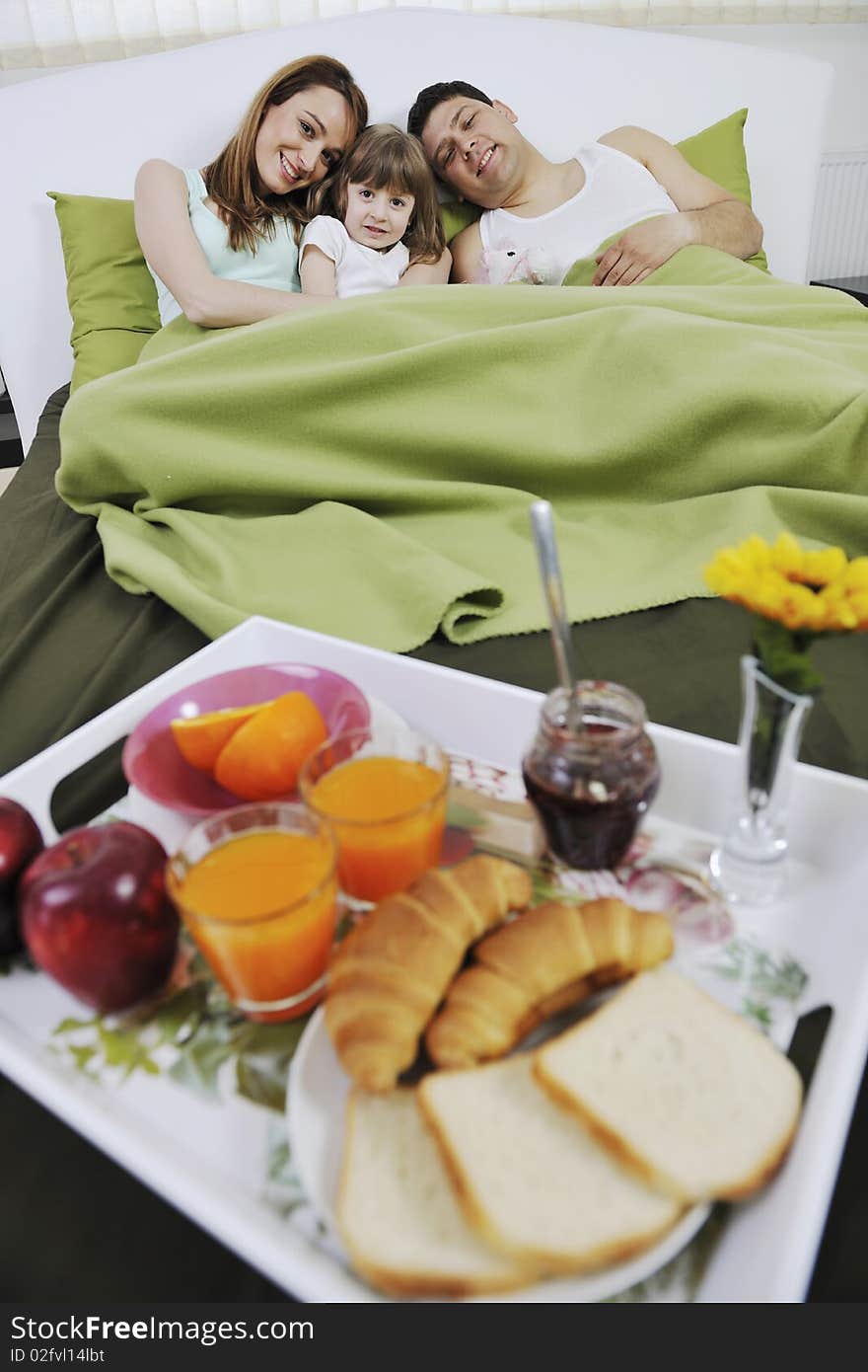 Happy young family eat breakfast in bed at morning