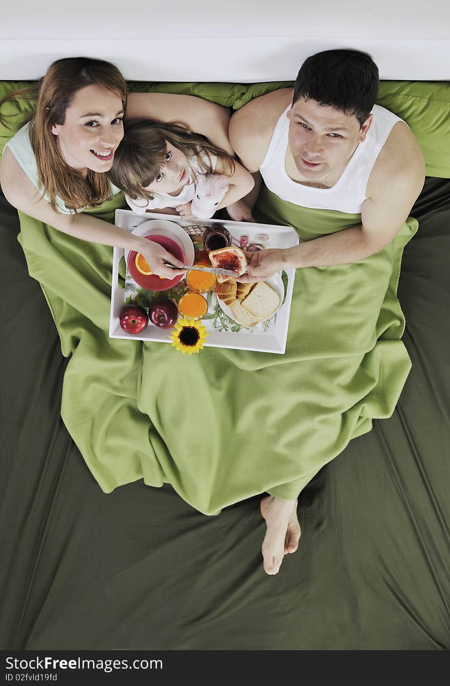 Happy young family eat breakfast in bed at morning