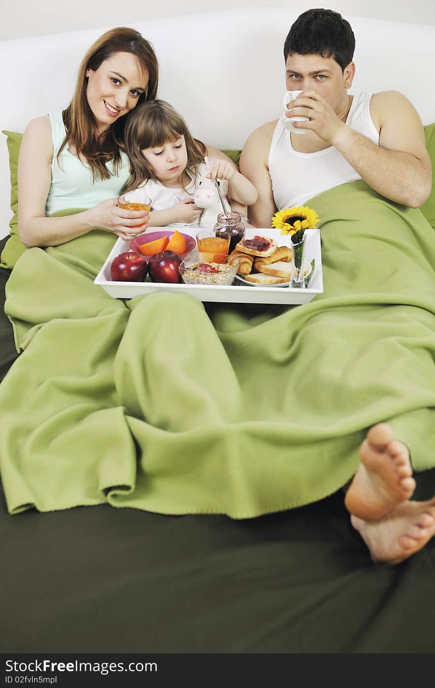 Happy young family eat breakfast in bed at morning