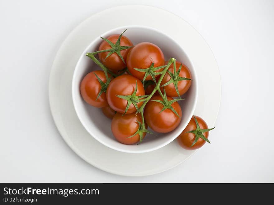 White bowl full of vine tomatoes. White bowl full of vine tomatoes