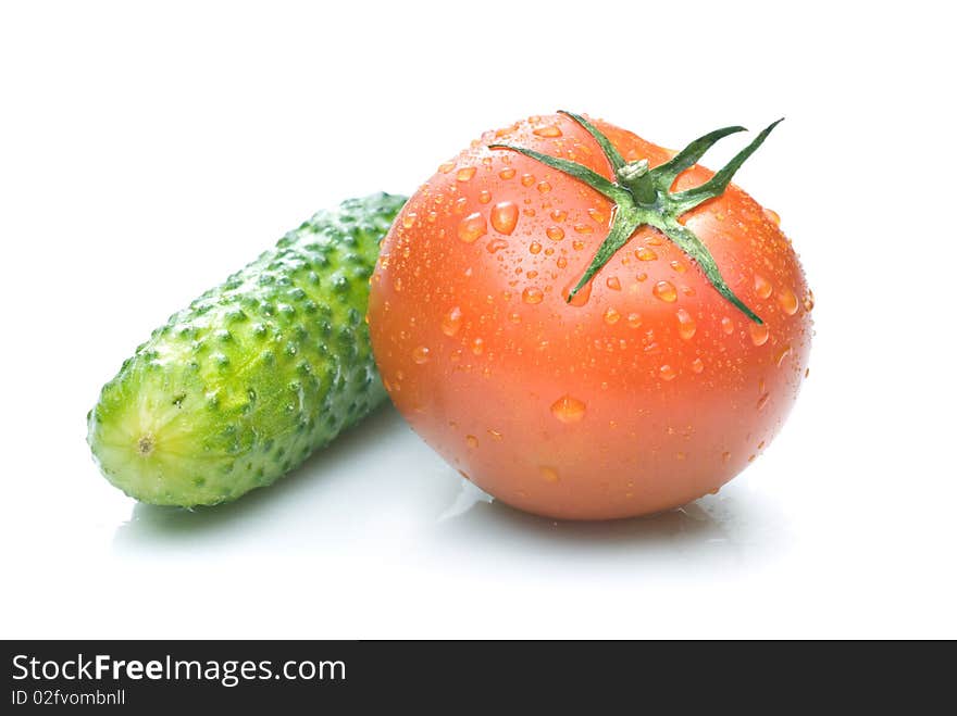 Red tomato and green cucumber with water drops