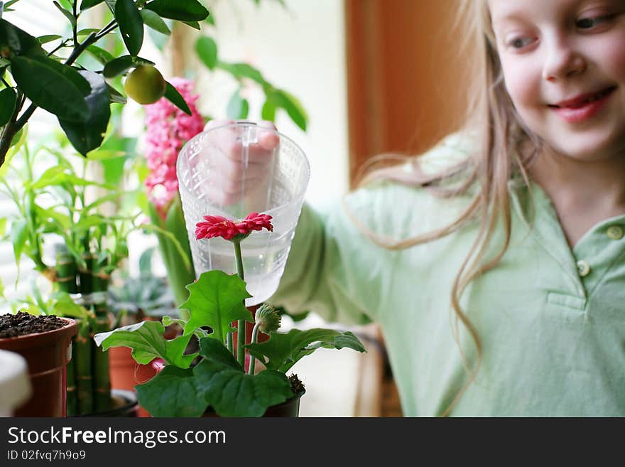 An image of a happy girl watering her flowers