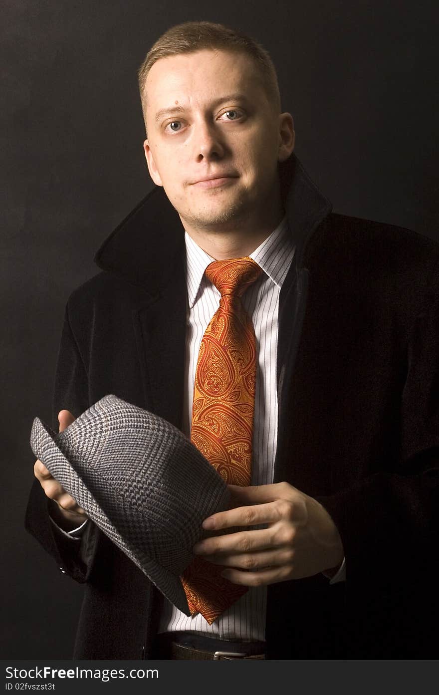 Young, elegant businessman, calm and confident face expression. Wearing shirt, tie and black coat, holding hat. Young, elegant businessman, calm and confident face expression. Wearing shirt, tie and black coat, holding hat.