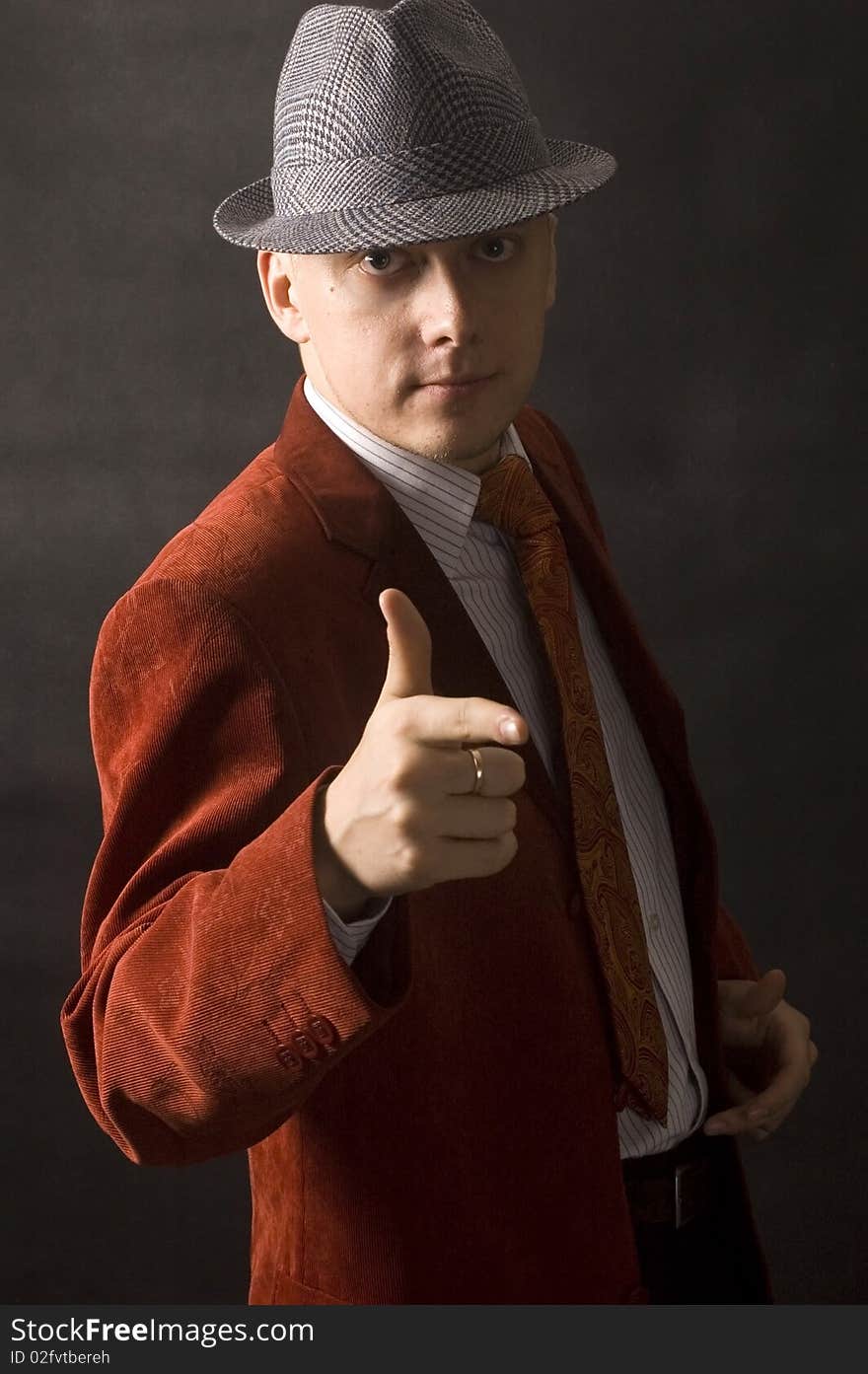 Handsome, young man with hand gesture. Wearing hat, red suit, shirt and red necktie. Serious and calm face expression. Handsome, young man with hand gesture. Wearing hat, red suit, shirt and red necktie. Serious and calm face expression.