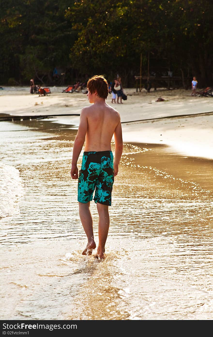 Young boy is walking along the beautiful beach in backlight. Young boy is walking along the beautiful beach in backlight