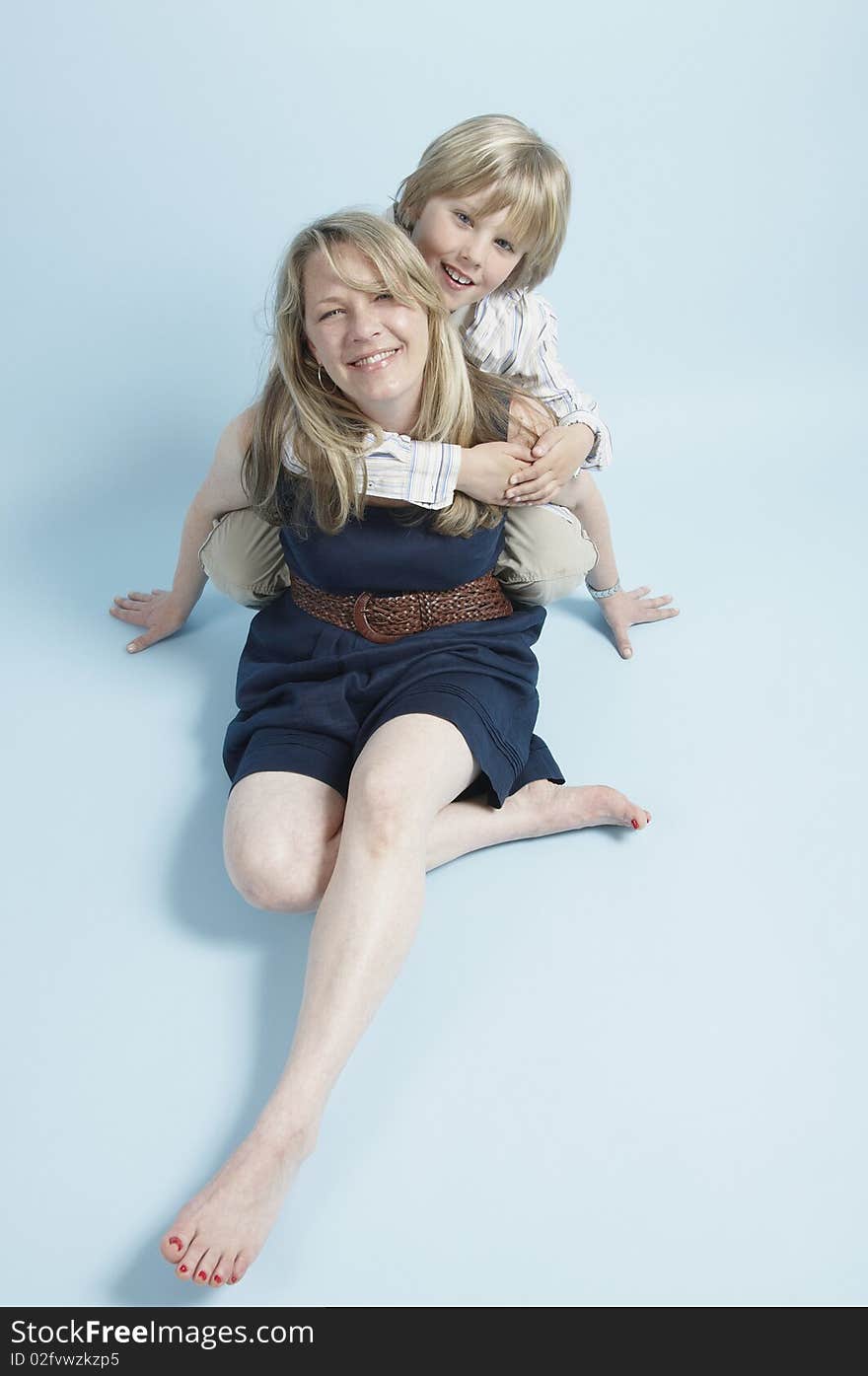 Blond blue eyed born hugging his mom who is seated on the floor. Blond blue eyed born hugging his mom who is seated on the floor