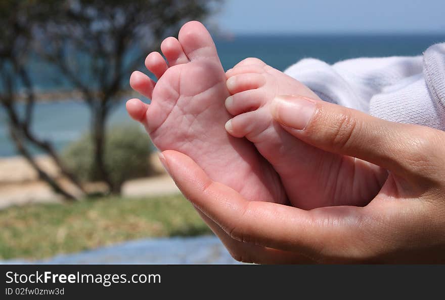 Mom is holding little feet of her son. Mom is holding little feet of her son