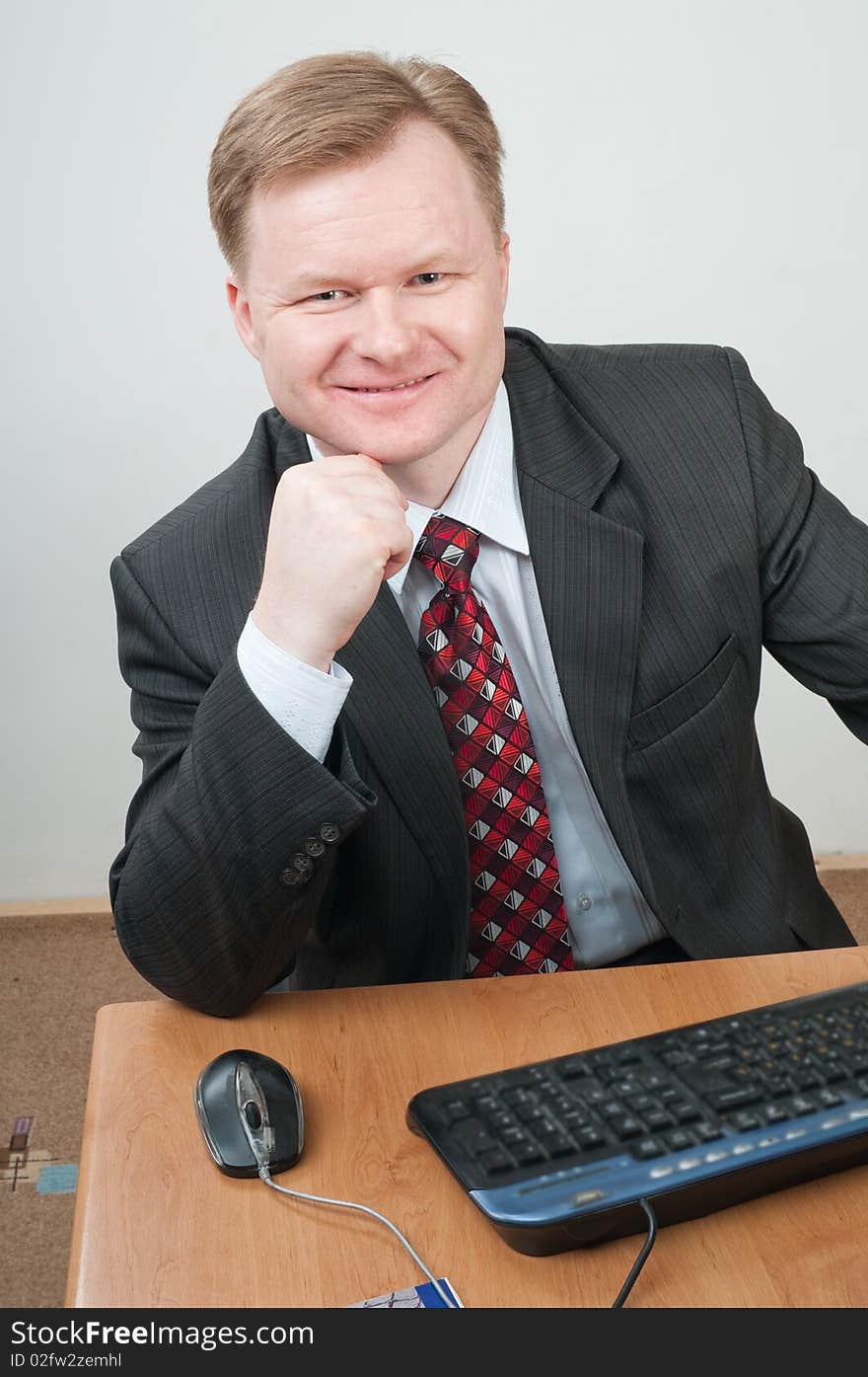 The man of forty five years in a grey suit and a red tie works on the computer. The man of forty five years in a grey suit and a red tie works on the computer.