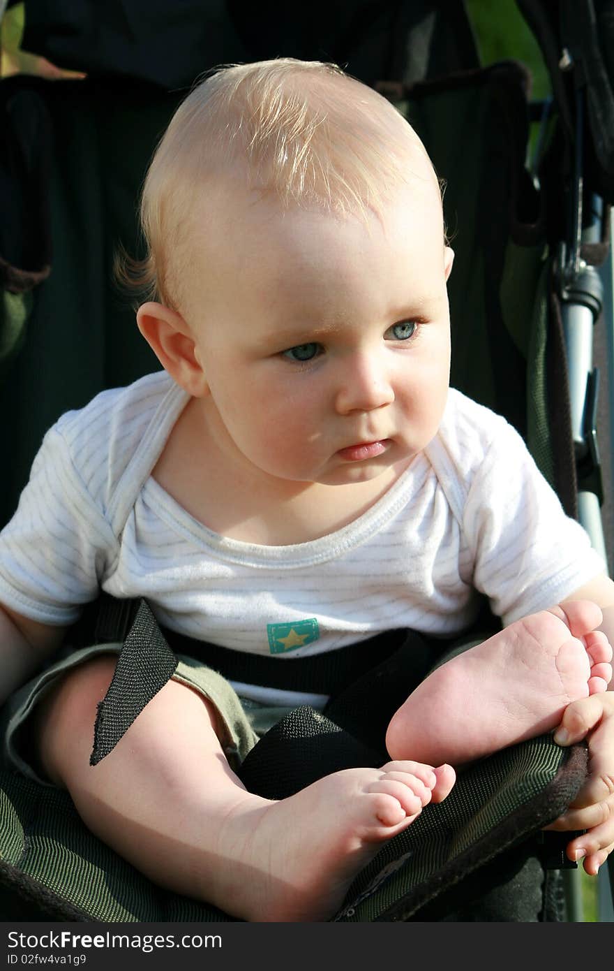 Seven months old baby boy sitting in a baby stroller. Seven months old baby boy sitting in a baby stroller.