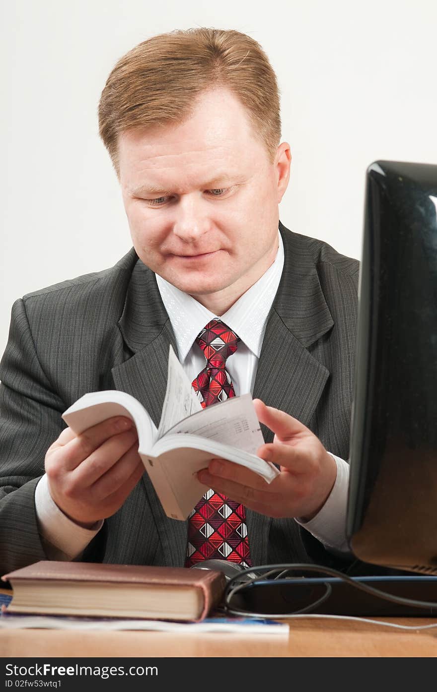 The man of forty five years in a grey suit and a red tie works on the computer. The man of forty five years in a grey suit and a red tie works on the computer.