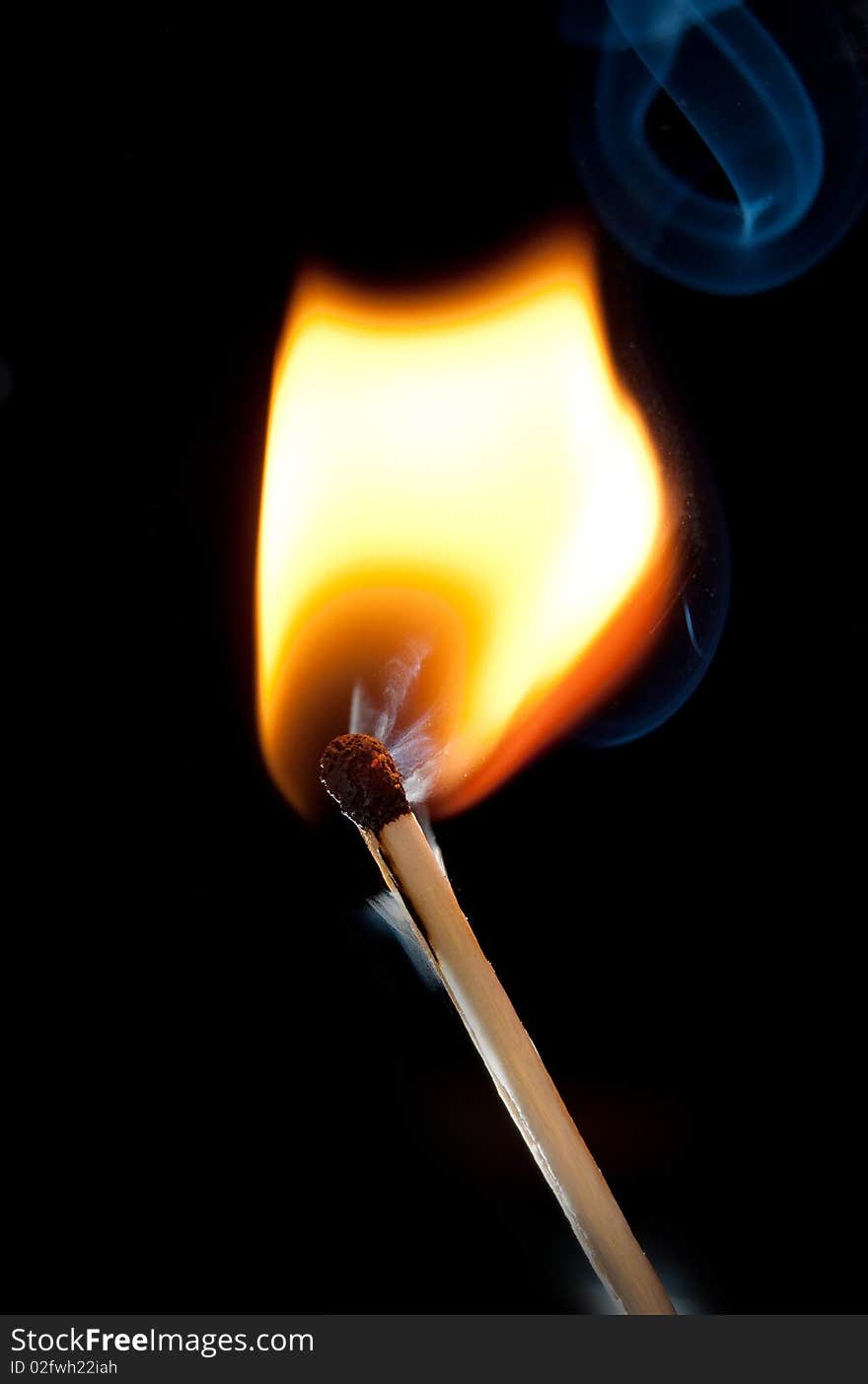 Burning match over black background