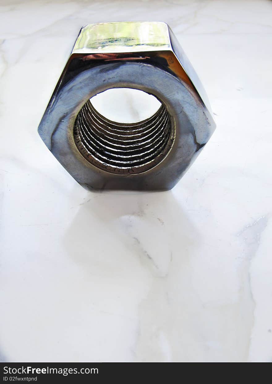 Detail of a metal nut on a marble background. Detail of a metal nut on a marble background