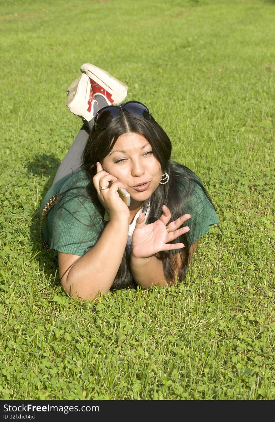 Beauty young woman lies on lawn and speaks by phone. Beauty young woman lies on lawn and speaks by phone