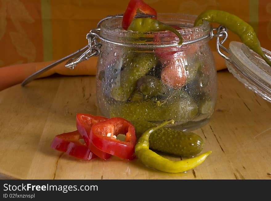 Pickles assortment in a glass jar, on light wood background. Pickles assortment in a glass jar, on light wood background