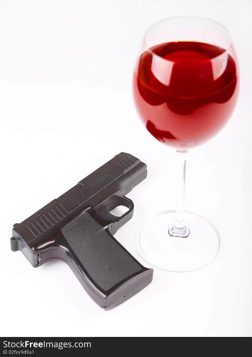 Closeup of pistol and glass of red wine isolated over white background. Closeup of pistol and glass of red wine isolated over white background