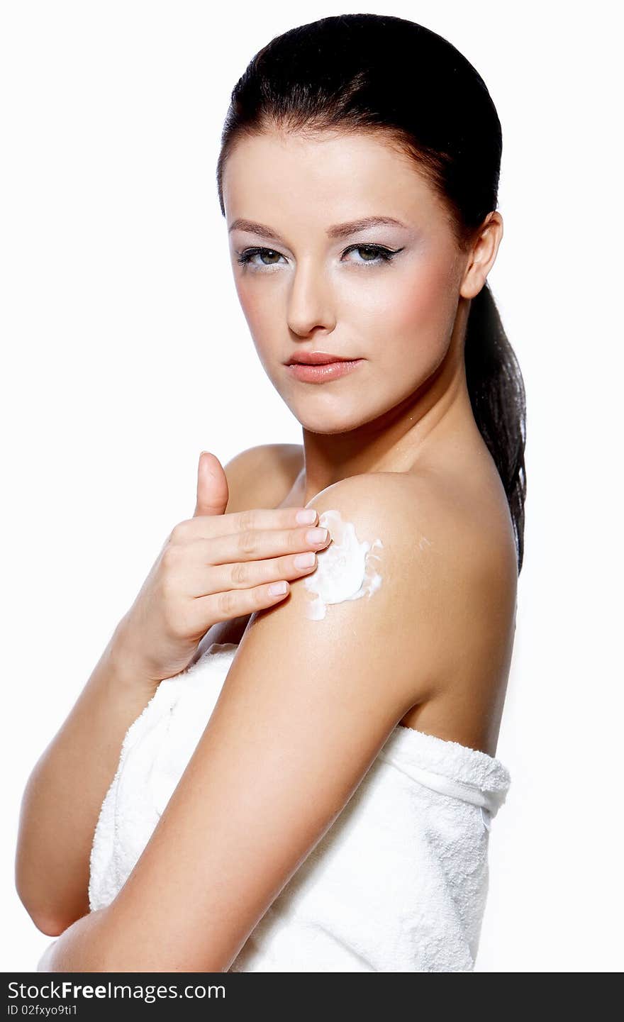 Portrait of a beautiful brunette woman applying cream on white background
