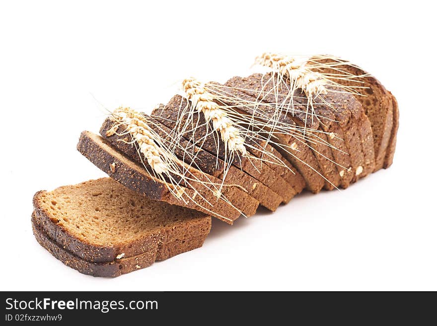 The cut bread on a white background with wheat