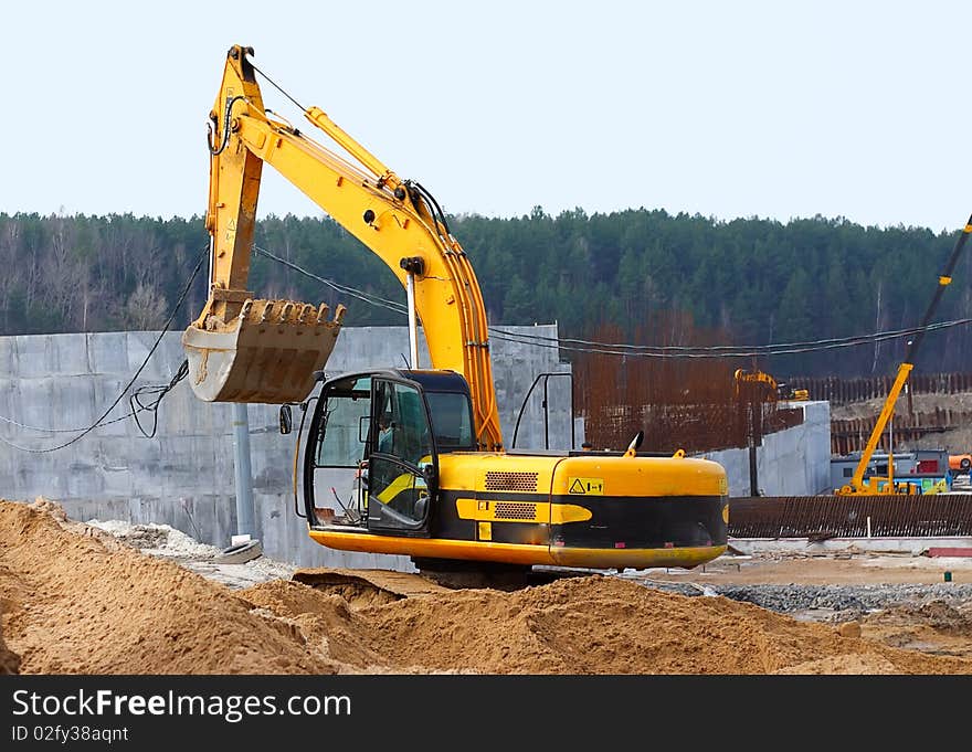 Old dredge digging the earth, photographed against the earth, the blue sky and a green bush