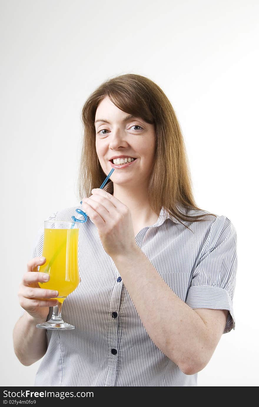 A vertical image of a pretty young woman with a glass of orange juice in her hand and sipping from a blue straw