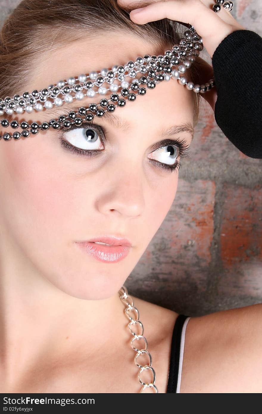 Young female model with silver jewellery against a brick wall background. Young female model with silver jewellery against a brick wall background