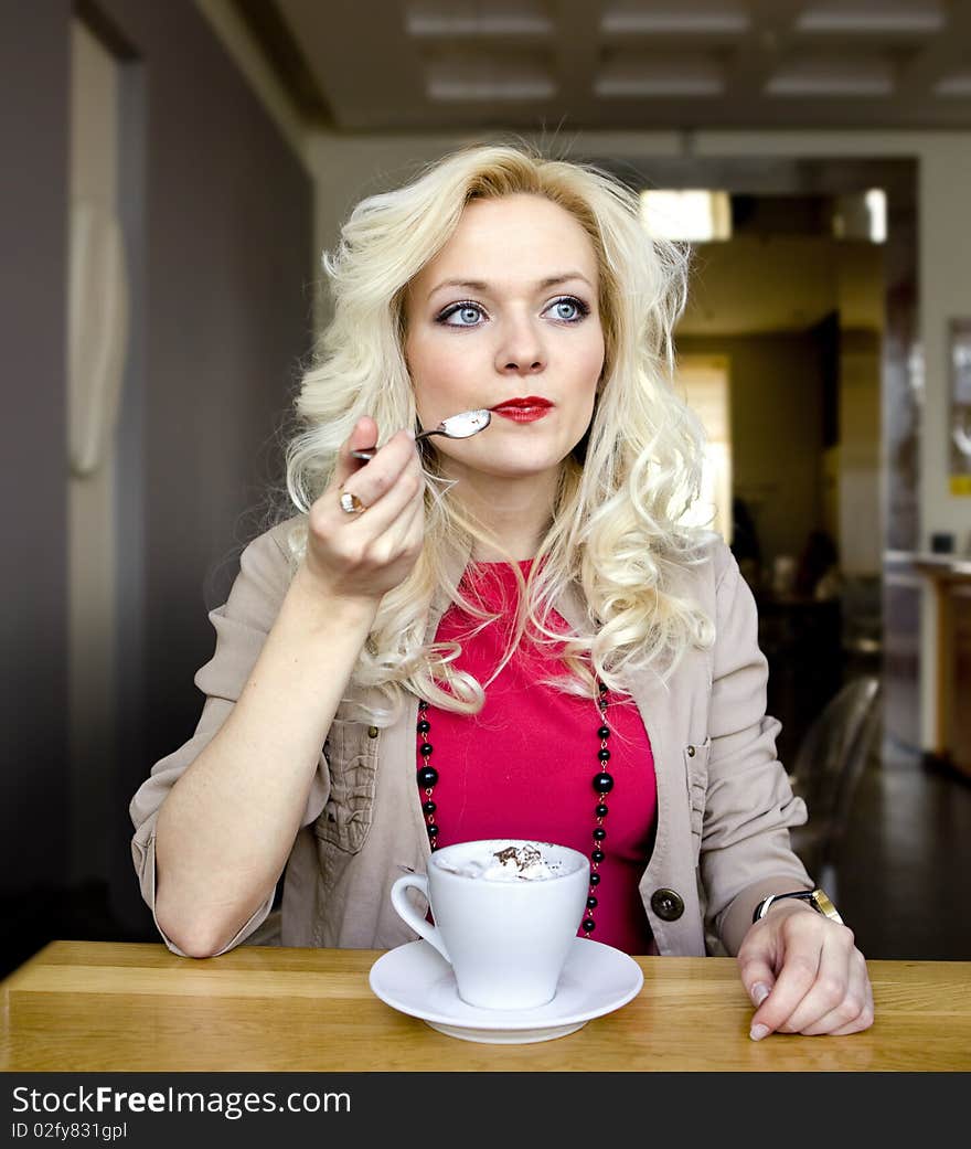 Young blonde in cafe at little table with cup of coffee. Young blonde in cafe at little table with cup of coffee