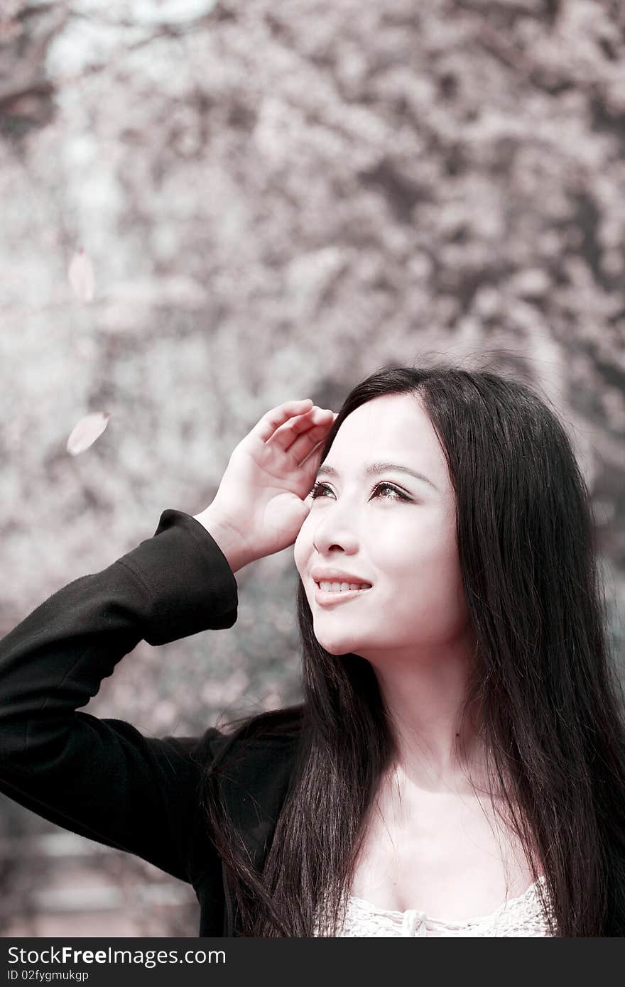 Young Asian woman with long hair sitting and enjoying the scenery in spring. This is the cherry blossom season. Young Asian woman with long hair sitting and enjoying the scenery in spring. This is the cherry blossom season.