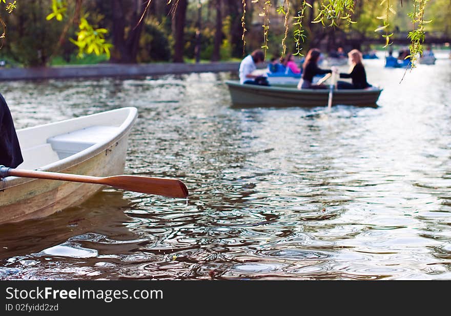 Boats on the river in a park with happy people enjoying a summer day