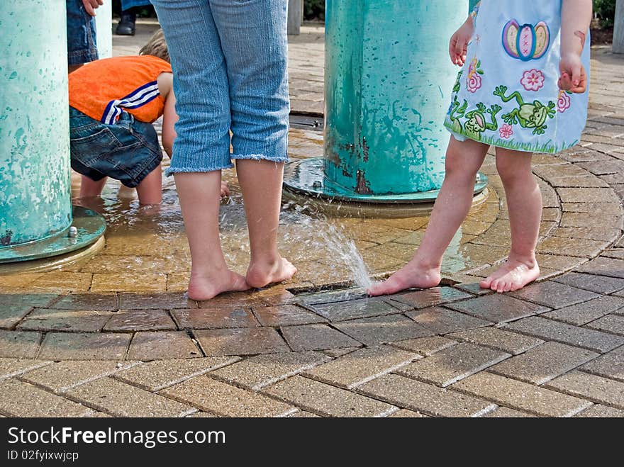 Kids with adult playing in a park fountain. Kids with adult playing in a park fountain.