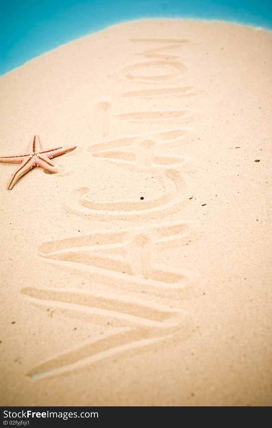 Vacation handwritten in sand and starfish