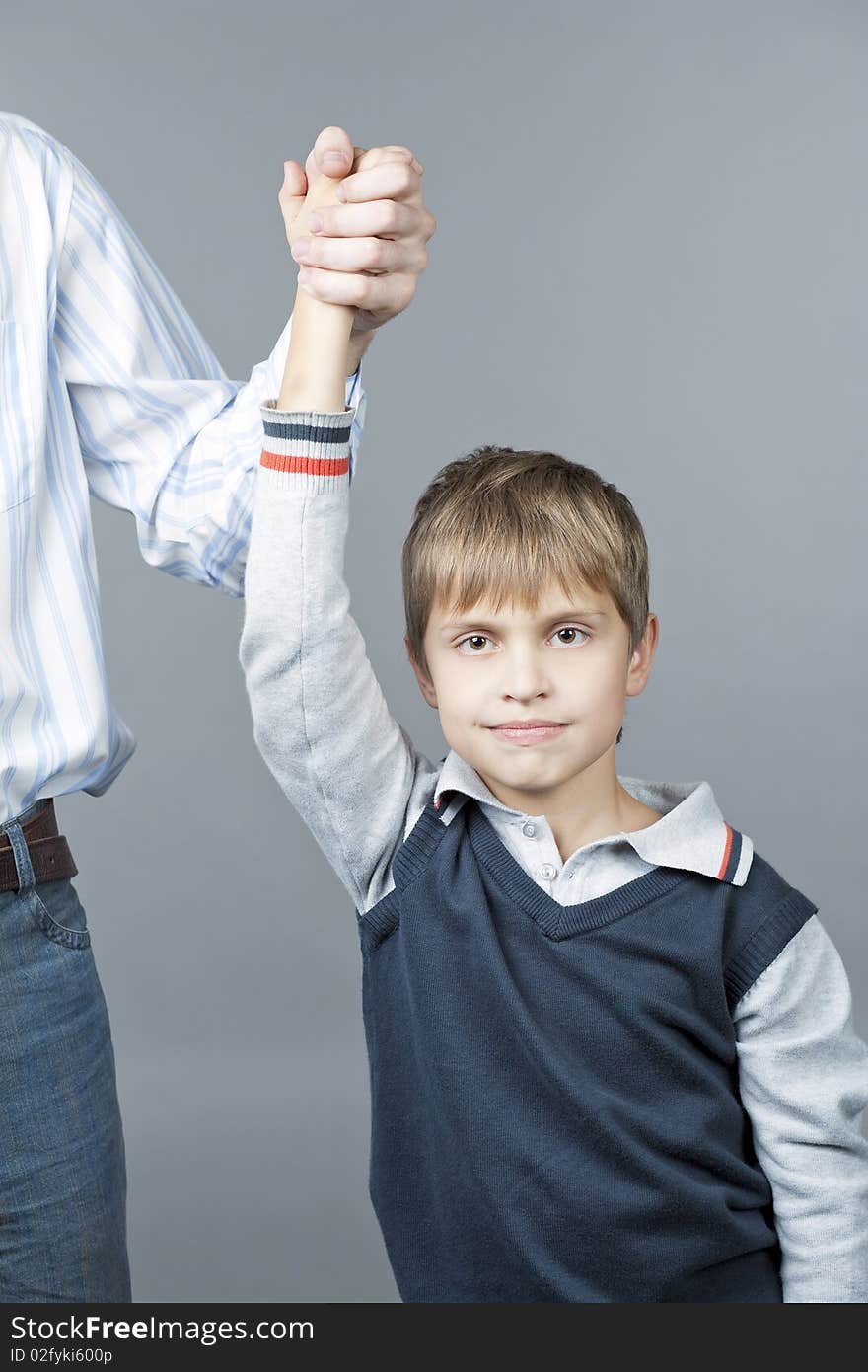 Young teenager boy with father near standing with happy facial expression and making winning sign with hand isolated over gray background. Young teenager boy with father near standing with happy facial expression and making winning sign with hand isolated over gray background