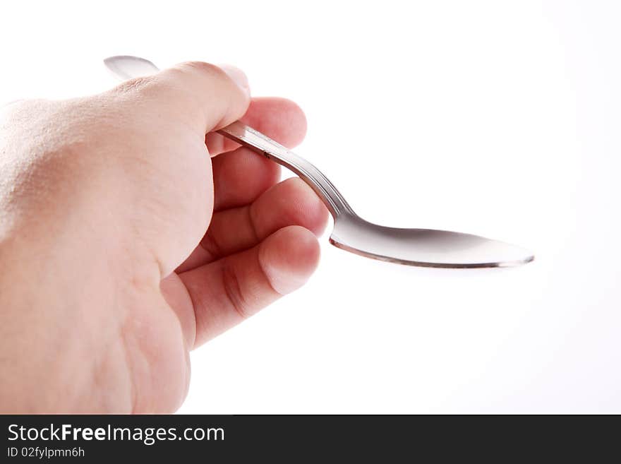 A man's hand holding an empty silver spoon on white background