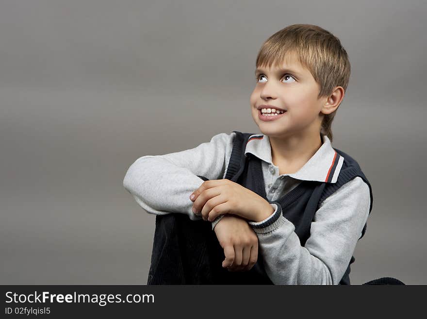 Smiling young caucasian teenager boy with calm face expression and looking up isolated over gray background. Smiling young caucasian teenager boy with calm face expression and looking up isolated over gray background