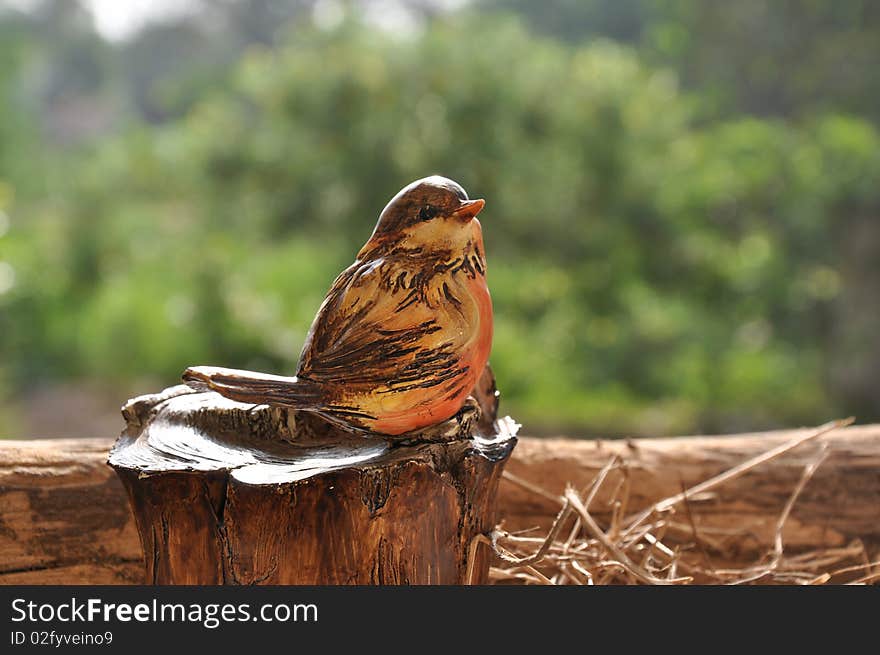 Tiny bird made of clay in woods background.