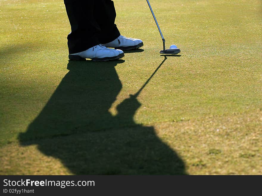 A golfer is about to putt the ball into the hole. A golfer is about to putt the ball into the hole.